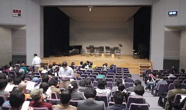 Empty stage, people finding their seats.